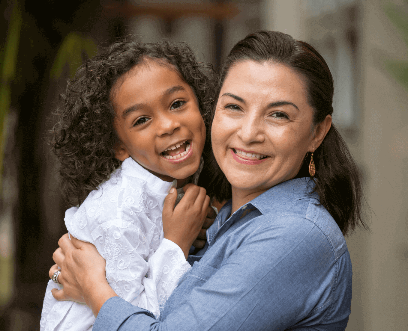 A woman and a young girl hugging and smiling and looking forward.